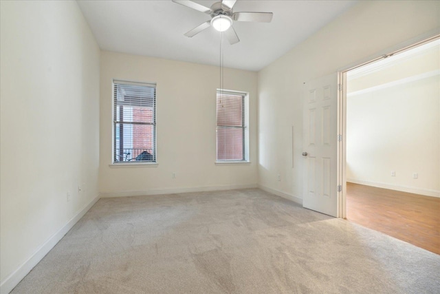 empty room with a ceiling fan, baseboards, and light carpet