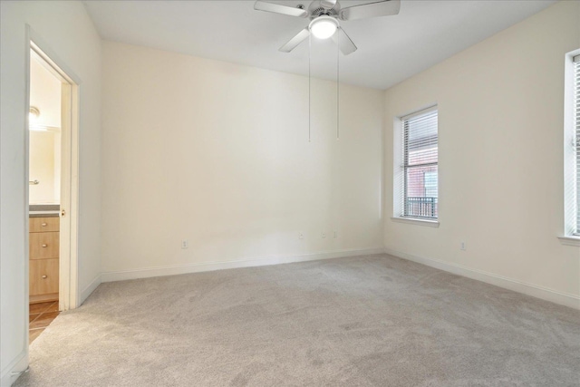 unfurnished room with light colored carpet, baseboards, and ceiling fan