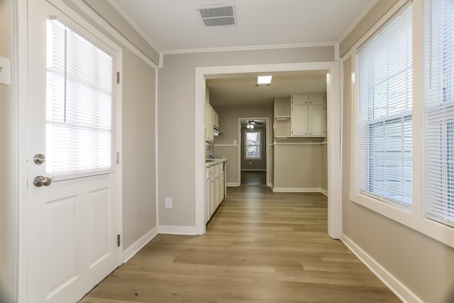 hallway with visible vents, a healthy amount of sunlight, and light wood finished floors