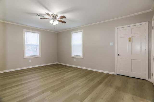 unfurnished room featuring a ceiling fan, baseboards, visible vents, ornamental molding, and light wood-type flooring