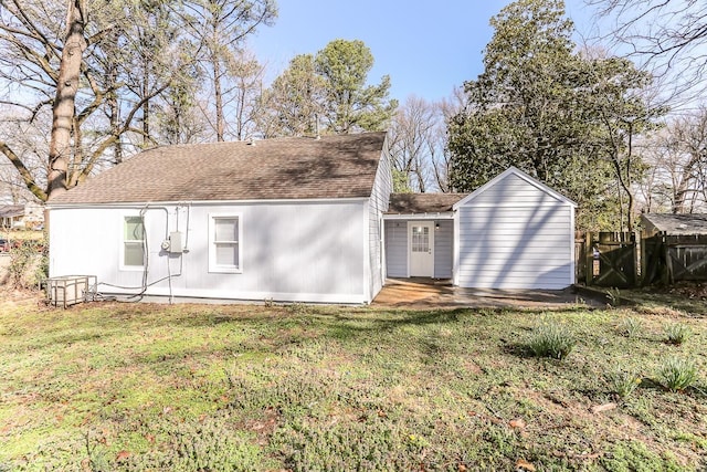 exterior space featuring a lawn, a shingled roof, and fence