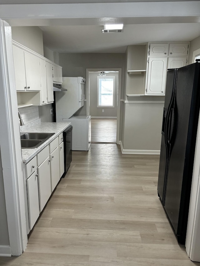 kitchen with black appliances, light wood-style flooring, visible vents, and a sink