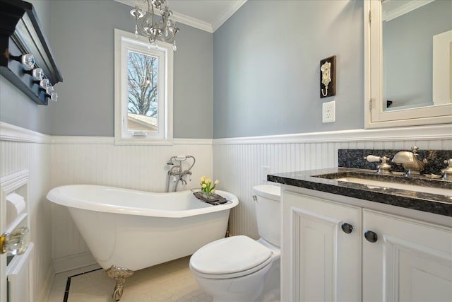 full bath with toilet, crown molding, wainscoting, a freestanding bath, and vanity