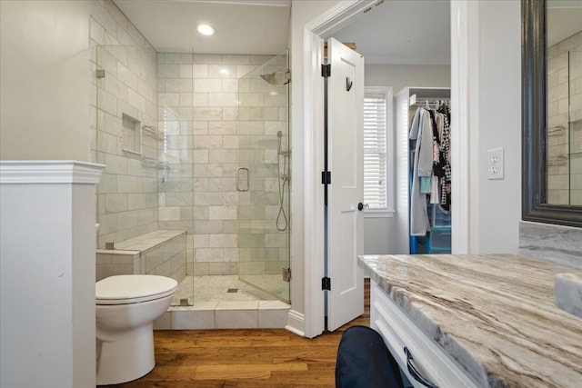 bathroom with toilet, a stall shower, wood finished floors, vanity, and a spacious closet