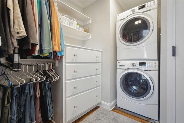 laundry room with wood finished floors, baseboards, and stacked washer and dryer