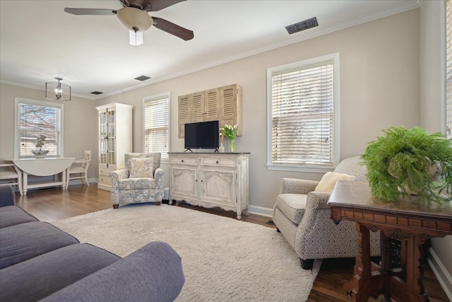 living area with a wealth of natural light, wood finished floors, ornamental molding, and a ceiling fan