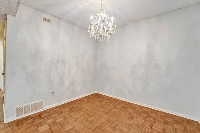 empty room with baseboards, visible vents, a textured ceiling, and an inviting chandelier