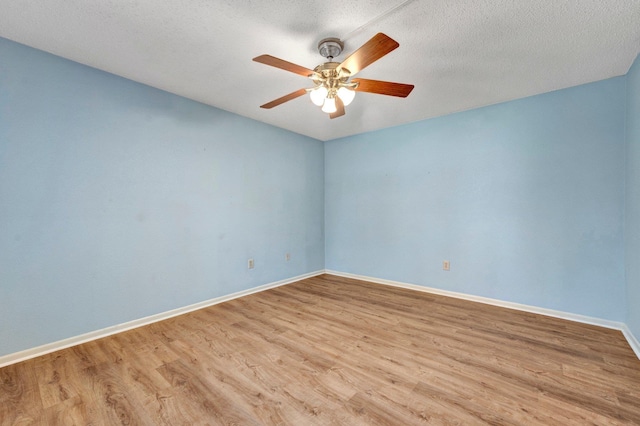 spare room featuring a textured ceiling, wood finished floors, baseboards, and ceiling fan