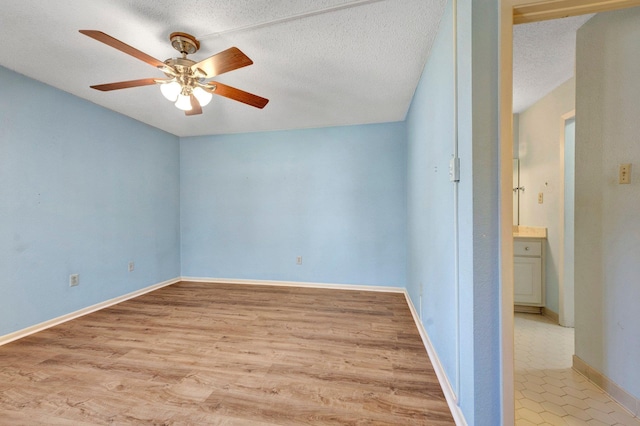 interior space featuring baseboards, a textured ceiling, light wood-type flooring, and ceiling fan