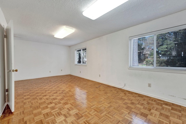 spare room with a textured ceiling and baseboards