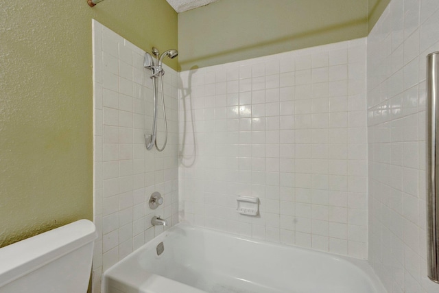 bathroom featuring toilet,  shower combination, and a textured wall