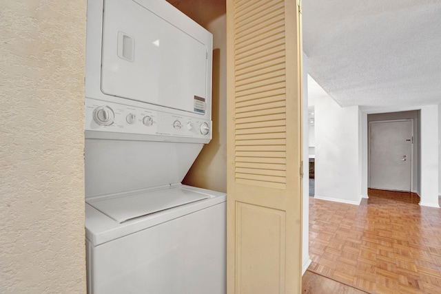 washroom with baseboards, laundry area, stacked washer / drying machine, a textured ceiling, and a textured wall