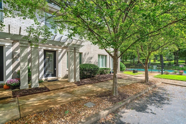 view of property exterior with brick siding, a fenced in pool, and fence