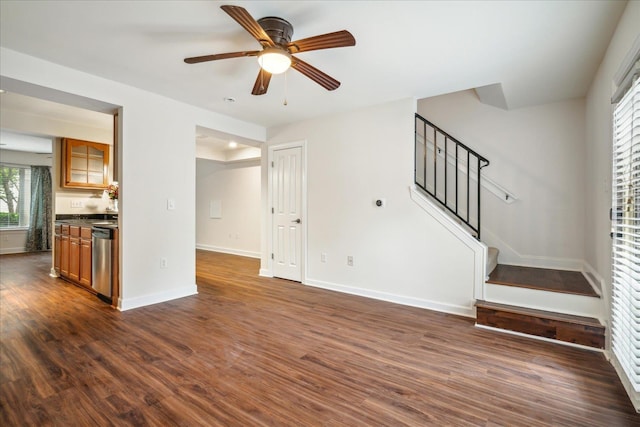 unfurnished living room featuring dark wood finished floors, a ceiling fan, stairs, and baseboards