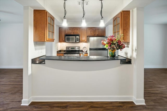 kitchen with glass insert cabinets, dark countertops, appliances with stainless steel finishes, and a peninsula