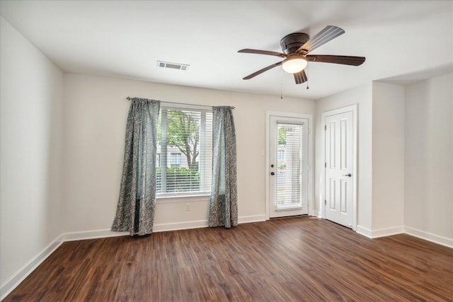 empty room featuring visible vents, baseboards, dark wood finished floors, and a ceiling fan