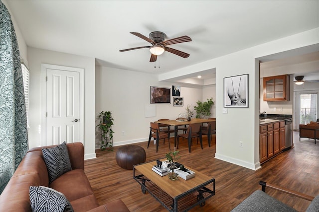 living room with baseboards, dark wood-type flooring, and ceiling fan