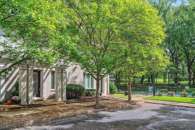 exterior space featuring a fenced in pool, a garage, fence, and brick siding