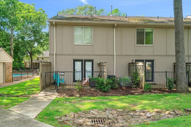 rear view of house featuring brick siding, a fenced in pool, and fence