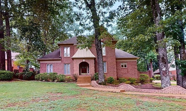 view of front facade with brick siding, roof with shingles, and a front lawn