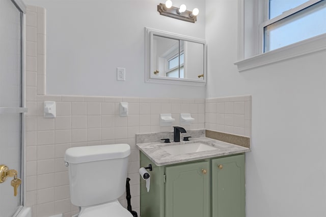 full bathroom with shower / washtub combination, toilet, vanity, wainscoting, and tile walls