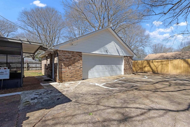 exterior space with a detached garage, brick siding, an outdoor structure, and fence