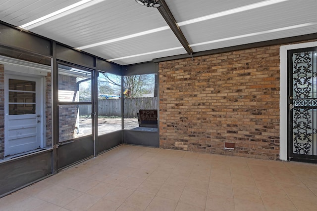 unfurnished sunroom featuring beam ceiling