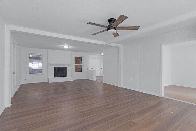 unfurnished living room featuring a fireplace, ceiling fan, and dark wood-style flooring