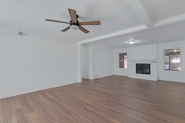 unfurnished living room with dark wood-style floors, a ceiling fan, visible vents, and baseboards