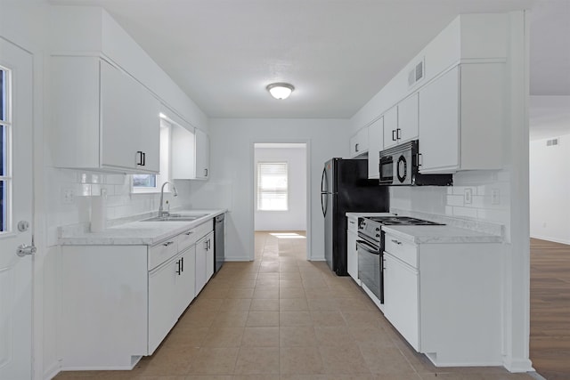 kitchen with black appliances, light countertops, visible vents, and a sink