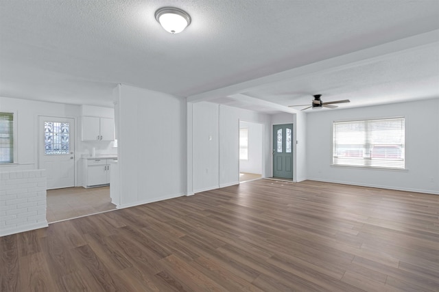 unfurnished living room with wood finished floors, plenty of natural light, ceiling fan, and a textured ceiling