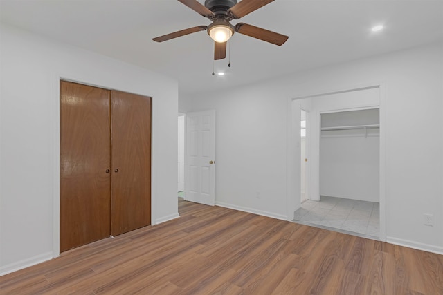 unfurnished bedroom featuring a closet, a ceiling fan, baseboards, and wood finished floors