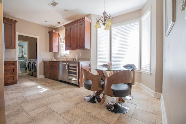 kitchen with beverage cooler, visible vents, washing machine and clothes dryer, light countertops, and a notable chandelier