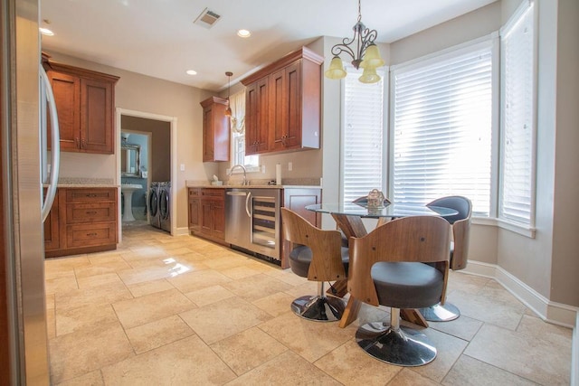 kitchen with visible vents, light countertops, freestanding refrigerator, a notable chandelier, and separate washer and dryer