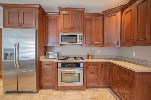 kitchen with light stone countertops, brown cabinets, and stainless steel appliances