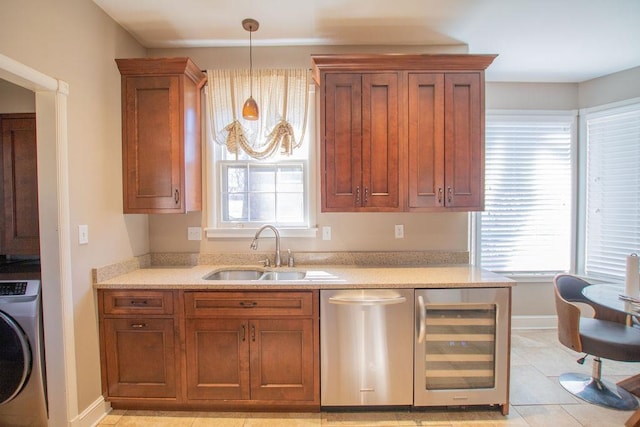 kitchen featuring beverage cooler, dishwasher, washer / dryer, hanging light fixtures, and a sink