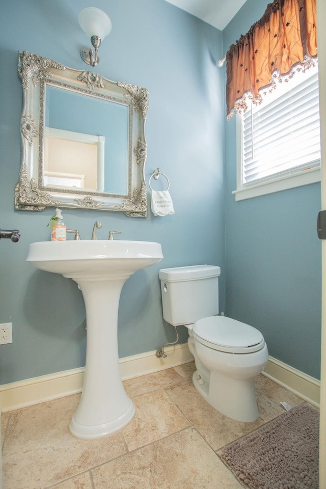 half bath featuring toilet and baseboards