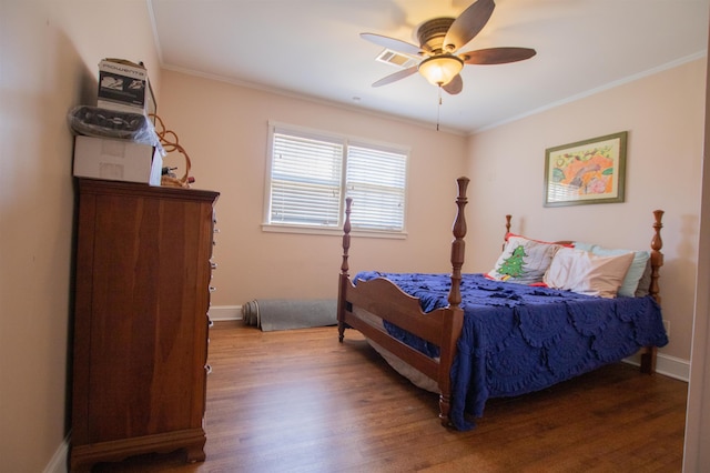 bedroom featuring baseboards, wood finished floors, visible vents, and ornamental molding