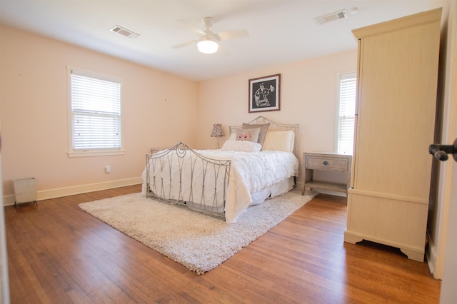 bedroom with visible vents, multiple windows, and wood finished floors