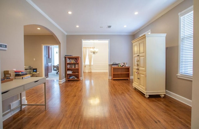 interior space with arched walkways, wood finished floors, and ornamental molding