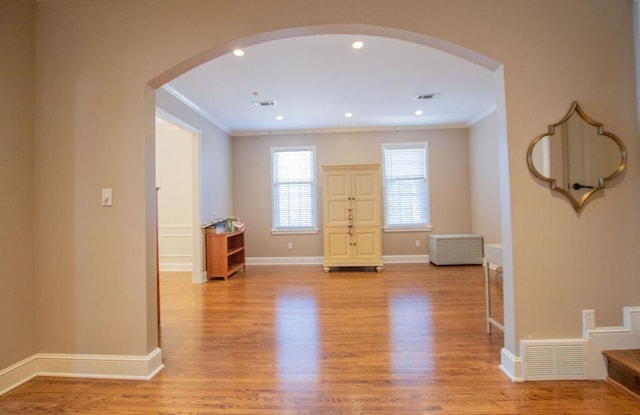 interior space with visible vents, arched walkways, light wood finished floors, and ornamental molding