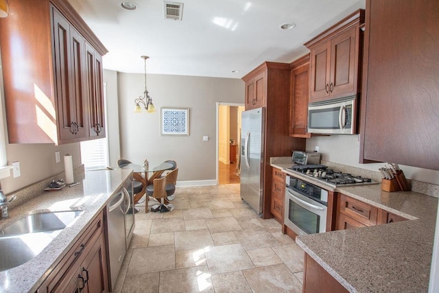 kitchen with light stone countertops, visible vents, a sink, appliances with stainless steel finishes, and brown cabinets