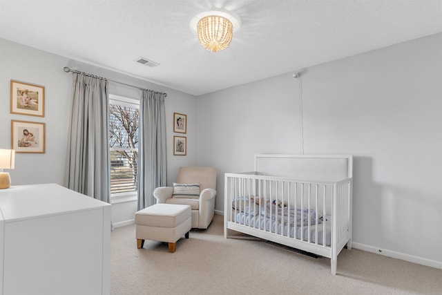 bedroom with visible vents, a nursery area, an inviting chandelier, baseboards, and light colored carpet