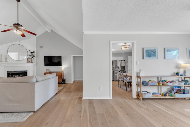 living area featuring a textured ceiling, light wood-style floors, a fireplace, and ceiling fan