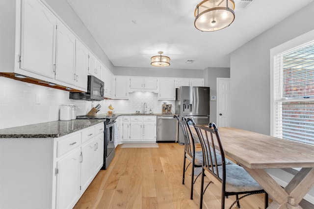 kitchen with white cabinets, plenty of natural light, appliances with stainless steel finishes, and a sink