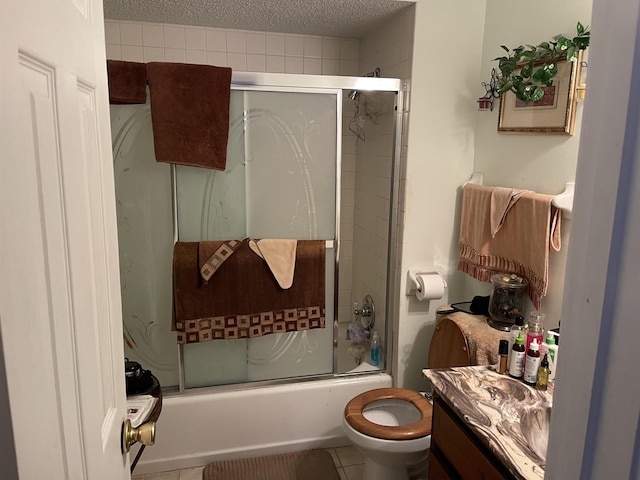 full bathroom featuring bath / shower combo with glass door, toilet, vanity, tile patterned floors, and a textured ceiling