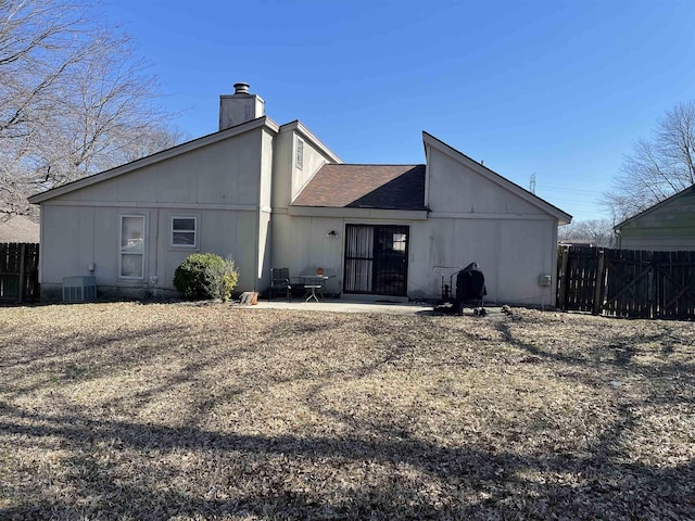 back of property featuring fence, roof with shingles, cooling unit, a chimney, and a patio area