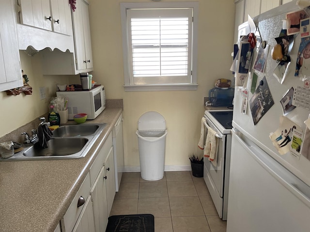 kitchen with white appliances, baseboards, light tile patterned flooring, a sink, and white cabinets