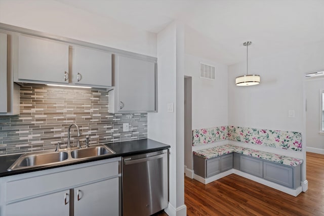 kitchen featuring visible vents, dark wood-type flooring, a sink, backsplash, and dishwasher