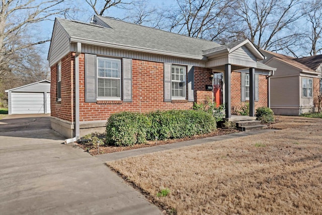 bungalow-style house featuring brick siding, a shingled roof, a detached garage, and an outdoor structure